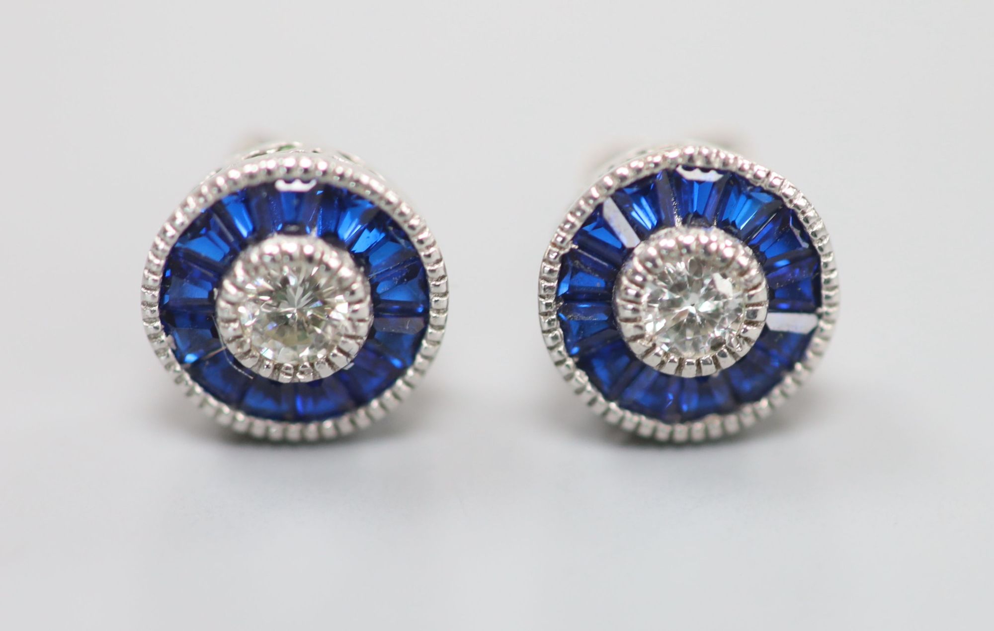 A pair of white metal (stamped China EJI) diamond and synthetic sapphire? set circular cluster earstuds, 10mm, gross 2.4 grams.